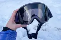 A person holding the Smith Squad Goggles over the snow