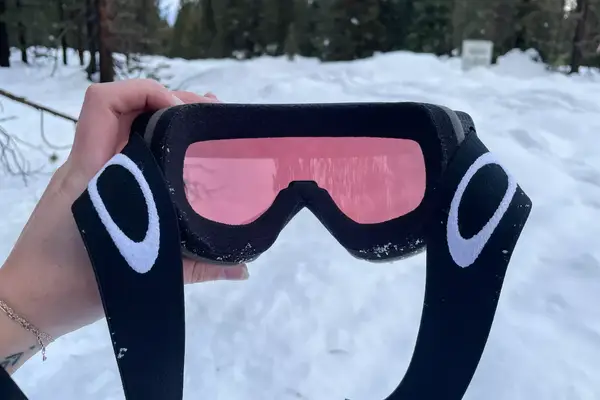 A person holding the Oakley Line Miner Pro L Snow Goggles outside in the snow