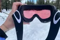 A person holding the Oakley Line Miner Pro L Snow Goggles outside in the snow