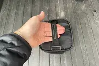 A person holding the carry bag for the Oakley Line Miner Pro L Snow Goggles