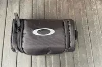 The carry bag for the Oakley Line Miner Pro L Snow Goggles on a wooden surface