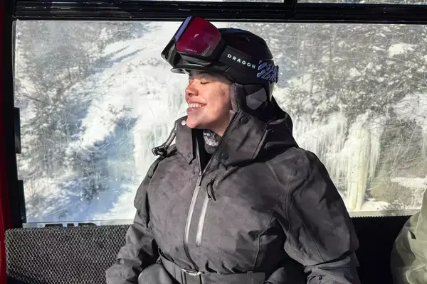 A person wearing the Dragon NFX Mag OTG goggles while on a ski lift