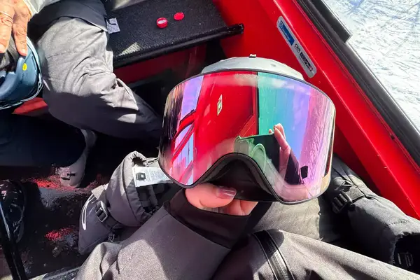 A person holding a helmet and the Dragon NFX Mag OTG goggles