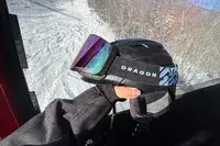 A person holding a helmet and the Dragon NFX Mag OTG goggles
