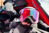 A person holding a helmet and the Dragon NFX Mag OTG goggles