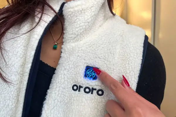 A person presses a button on the Ororo Women’s Heated Recycled Fleece Vest