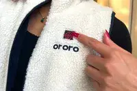 A person presses the power button on the Ororo Women’s Heated Recycled Fleece Vest