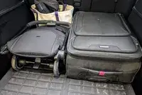 A folded Joolz Aer+ Lightweight Stroller, a suitcase and a tote bag placed in the trunk of a car