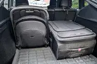 A folded Joolz Aer+ Lightweight Stroller and a travel suitcase in the trunk of a vehicle arranged side by side in an organized manner