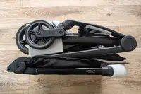A folded Joolz Aer+ Lightweight Stroller resting on a wooden floor showing compact wheels and frame