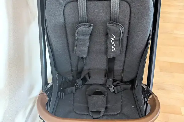 A closeup of Nuna TRVL LX Stroller seat with a harness and branding on the straps