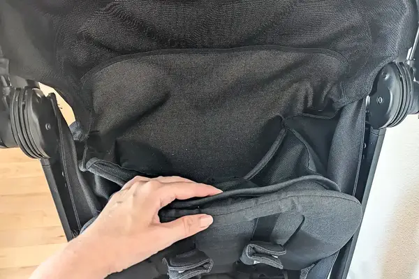Closeup of a hand adjusting the seat fabric of Nuna TRVL LX Stroller