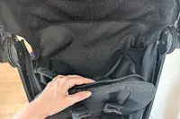 Closeup of a hand adjusting the seat fabric of Nuna TRVL LX Stroller