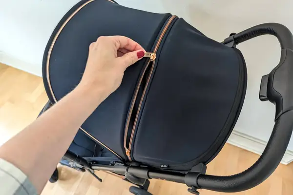 A person zipping a compartment on the Peg Perego Volo Compact Stroller canopy
