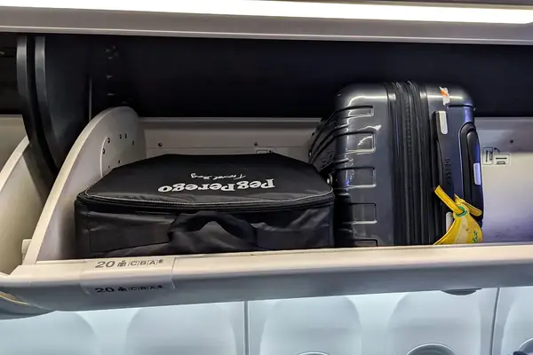 The Peg Perego Volo Compact Stroller packed into a storage bag in an airplane overhead compartment