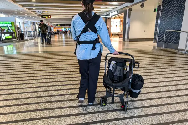 A person wheels the Doona + Car Seat and Stroller through an airport