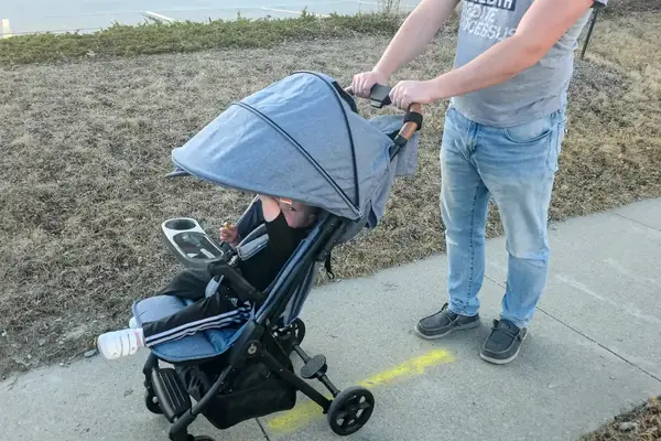 A person pushes a child in the Zoe The Traveler Stroller