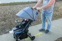 A person pushes a child in the Zoe The Traveler Stroller