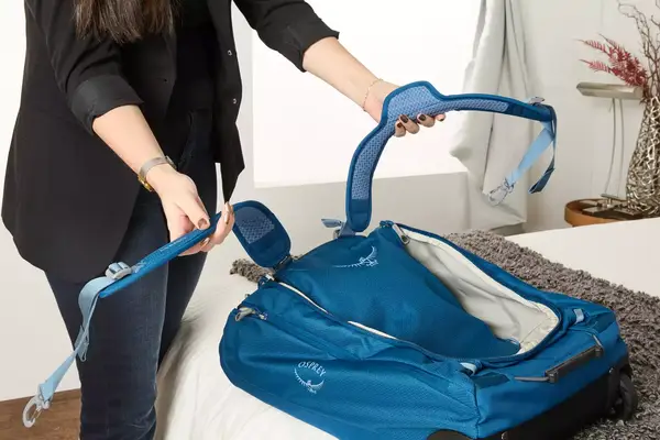 A person holding the straps of the Osprey Daylite Wheeled Duffel 40L