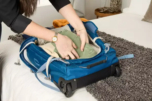 Two hands putting items into the Osprey Daylite Wheeled Duffel 40L