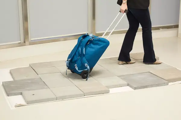 A person wheeling the Osprey Daylite Wheeled Duffel 40L on a tile platform 