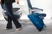 A person wheeling the Osprey Daylite Wheeled Duffel 40L through an aisle