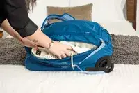 A person placing items into the Osprey Daylite Wheeled Duffel 40L