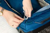 Two hands holding a part of the Osprey Daylite Wheeled Duffel 40L