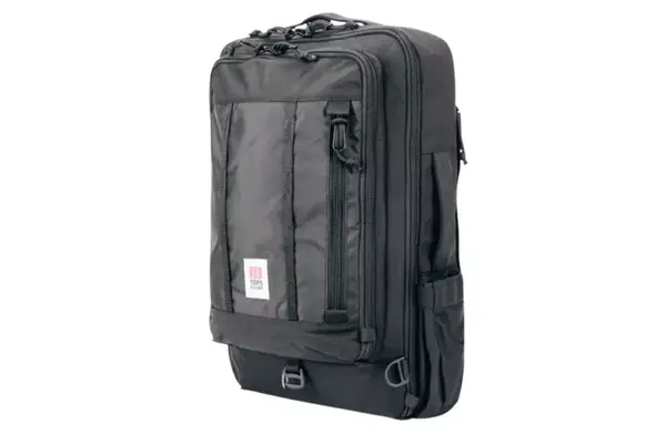 A person places the Cotopaxi Allpa 42L Travel Pack into an overhead compartment
