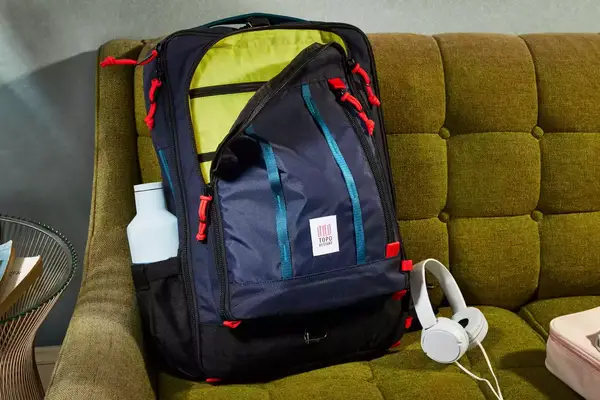 A person places a laptop into the Cotopaxi Allpa 42L Travel Pack