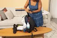 A person places a water bottle into the Cotopaxi Allpa 42L Travel Pack