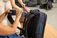 A person secures a strap on the Cotopaxi Allpa 42L Travel Pack