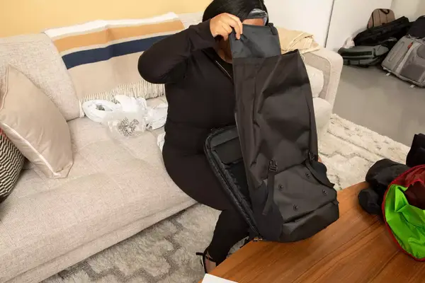 A person carries the Away The Outdoor Convertible Backpack 45L by the shoulder strap