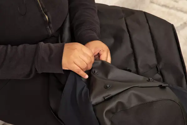 A person places the Away F.A.R. Convertible Backpack 45L into an overhead compartment