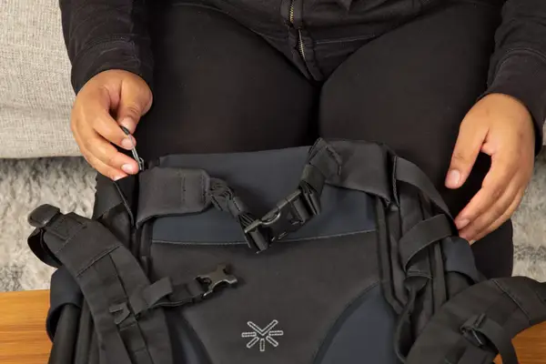 A person places the Away F.A.R. Convertible Backpack 45L under a seat