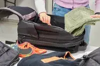 Person adding clothes to Nomatic Travel Pack Laptop Bag 20L