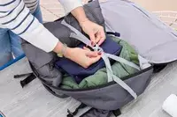 A person secures travel items in the Pacsafe Venturesafe EXP45 Anti-Theft Carry-On Travel Pack