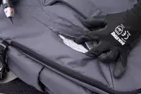 A person slices the Pacsafe Venturesafe EXP45 Anti-Theft Carry-On Travel Pack with a box cutter