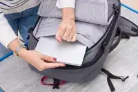 A person places a tablet into the Pacsafe Venturesafe EXP45 Anti-Theft Carry-On Travel Pack