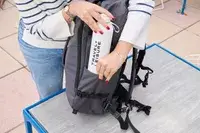 A person places a water bottle into the Pacsafe Venturesafe EXP45 Anti-Theft Carry-On Travel Pack