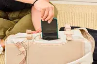 A person places a cell phone into the Calpak Terra 26L Laptop Duffel Backpack