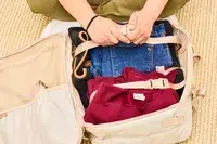 A person secures clothing inside the Calpak Terra 26L Laptop Duffel Backpack