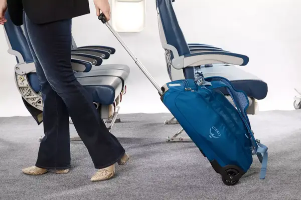 A person wheeling the Osprey Daylite Wheeled Duffel 40L through an aisle