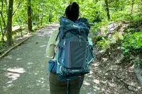 Person wearing a REI Co-op Traverse 60 Pack walking along a forested path