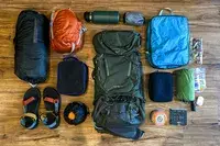 Camping gear arranged on a wooden floor including a Osprey Kestrel 58L Men