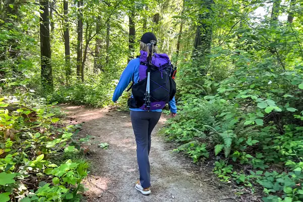 A person with a ULA Equipment Circuit walking on a forest trail surrounded by trees and plants