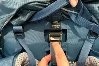 Finger adjusting a strap on a REI Co-op Traverse 60 Pack with a label visible