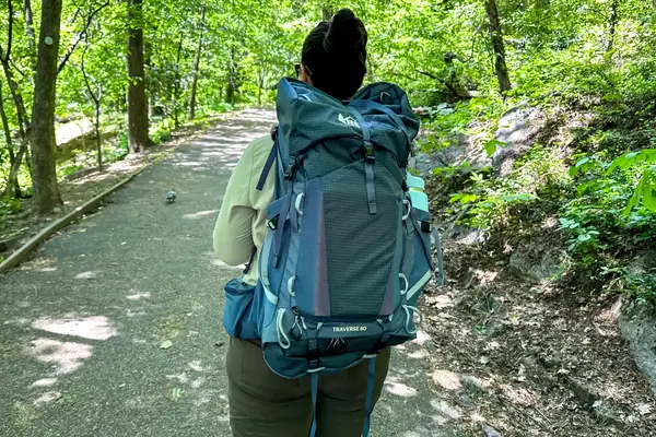 Person wearing a REI Co-op Traverse 60 Pack walking along a forested path