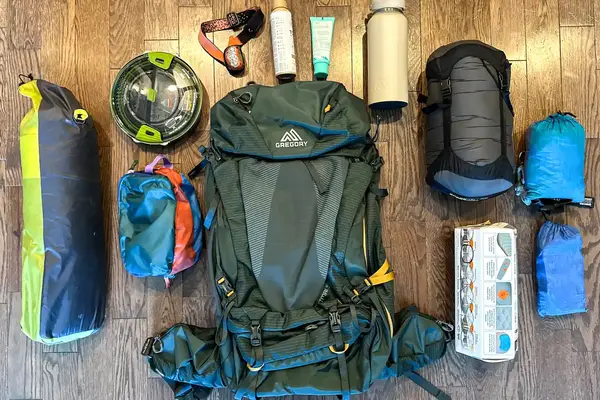 Camping gear laid out, includes Gregory Katamai 55 - Hiking Backpack, sleeping bag, and other equipment
