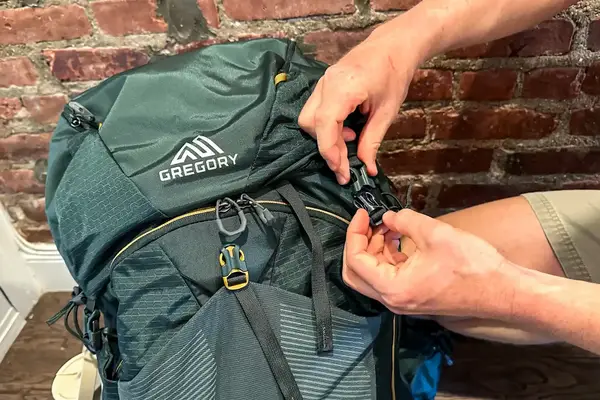 Hands adjusting a buckle on a green Gregory Katamai 55 - Hiking Backpack 